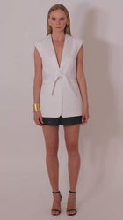 Model wearing the Roza white sleeveles  blazer with belt by Leochèle turns and walks out of frame