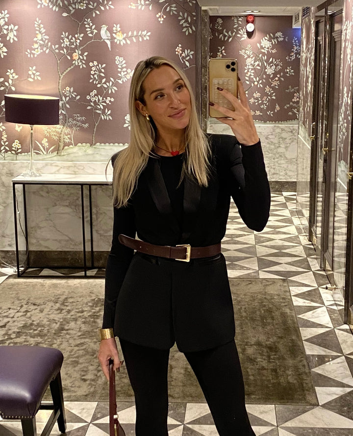 Woman taking a mirror selfie in the Roza sleeveless blazer in black styled with a brown belt